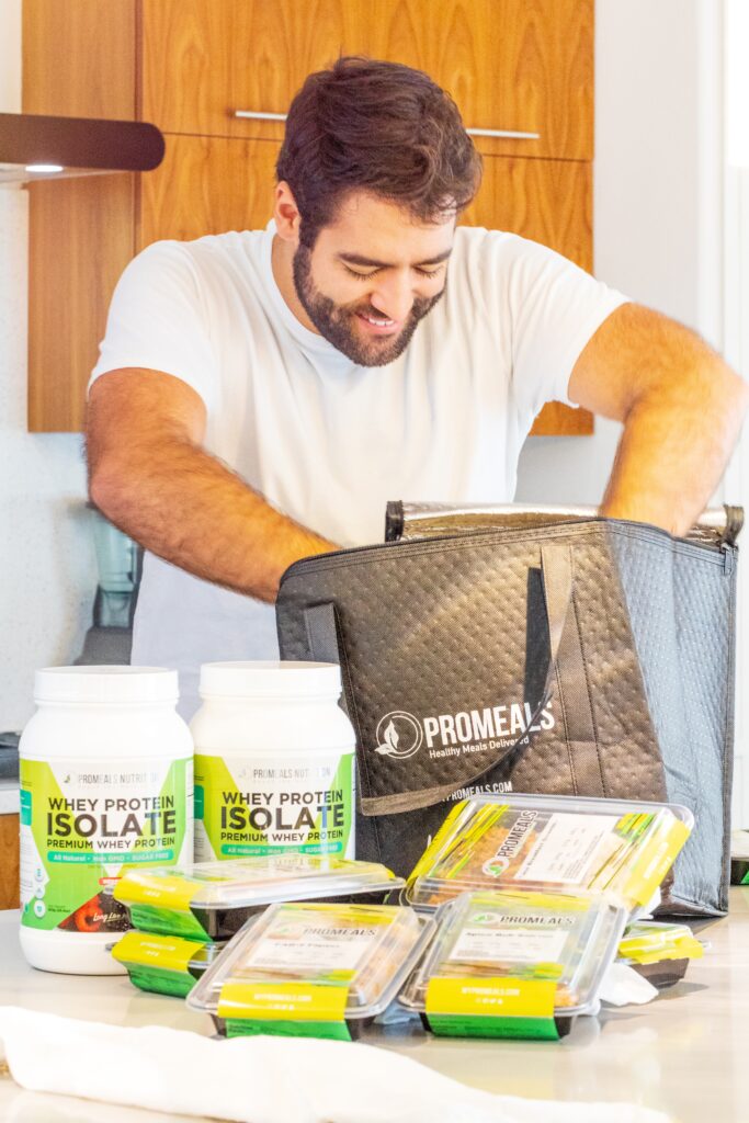 Busy professional opening a ProMeals box with high-protein prepared meals